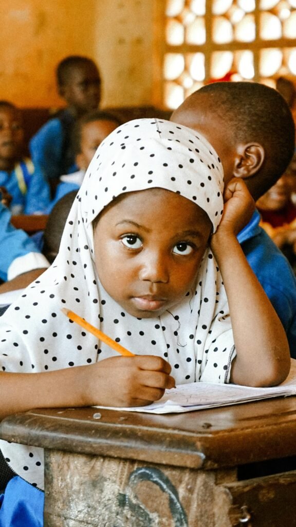 Young girl focused on writing in a vibrant classroom environment.